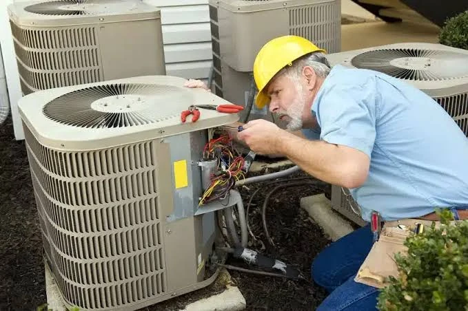 Technician examining the service panel of an outdoor cooling unit