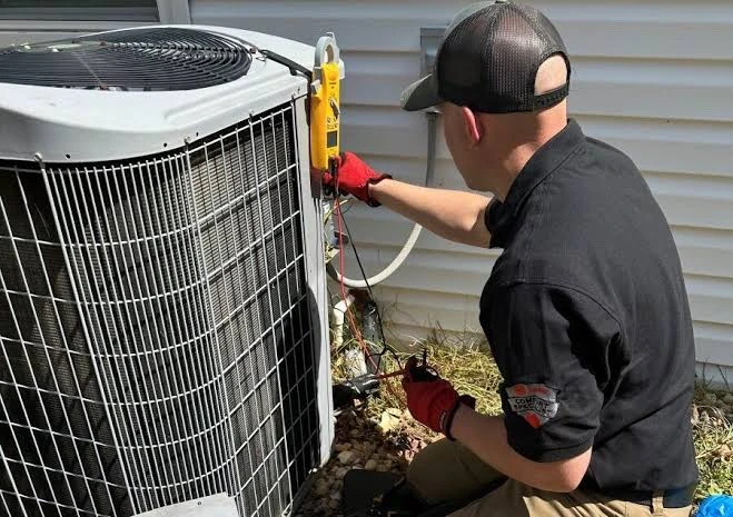 Technician using diagnostic equipment beside a residential condenser