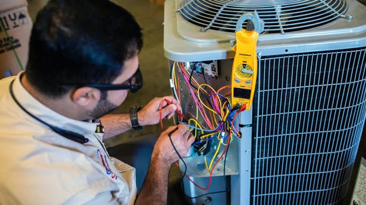 Technician testing air conditioner wiring with an electrical meter