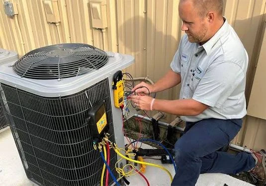 Technician taking measurements beside an outdoor air conditioning unit