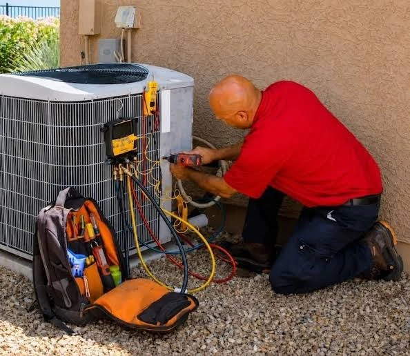 Technician working on a condenser with gauges and service tools