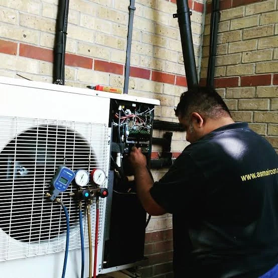 Technician checking an air conditioning control panel and pressure gauges