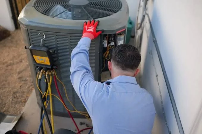 Technician inspecting an outdoor condenser from above